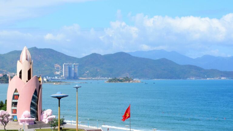 Tram Huong Tower facing the coastline of Nha Trang with blue sea and mountains in the background.