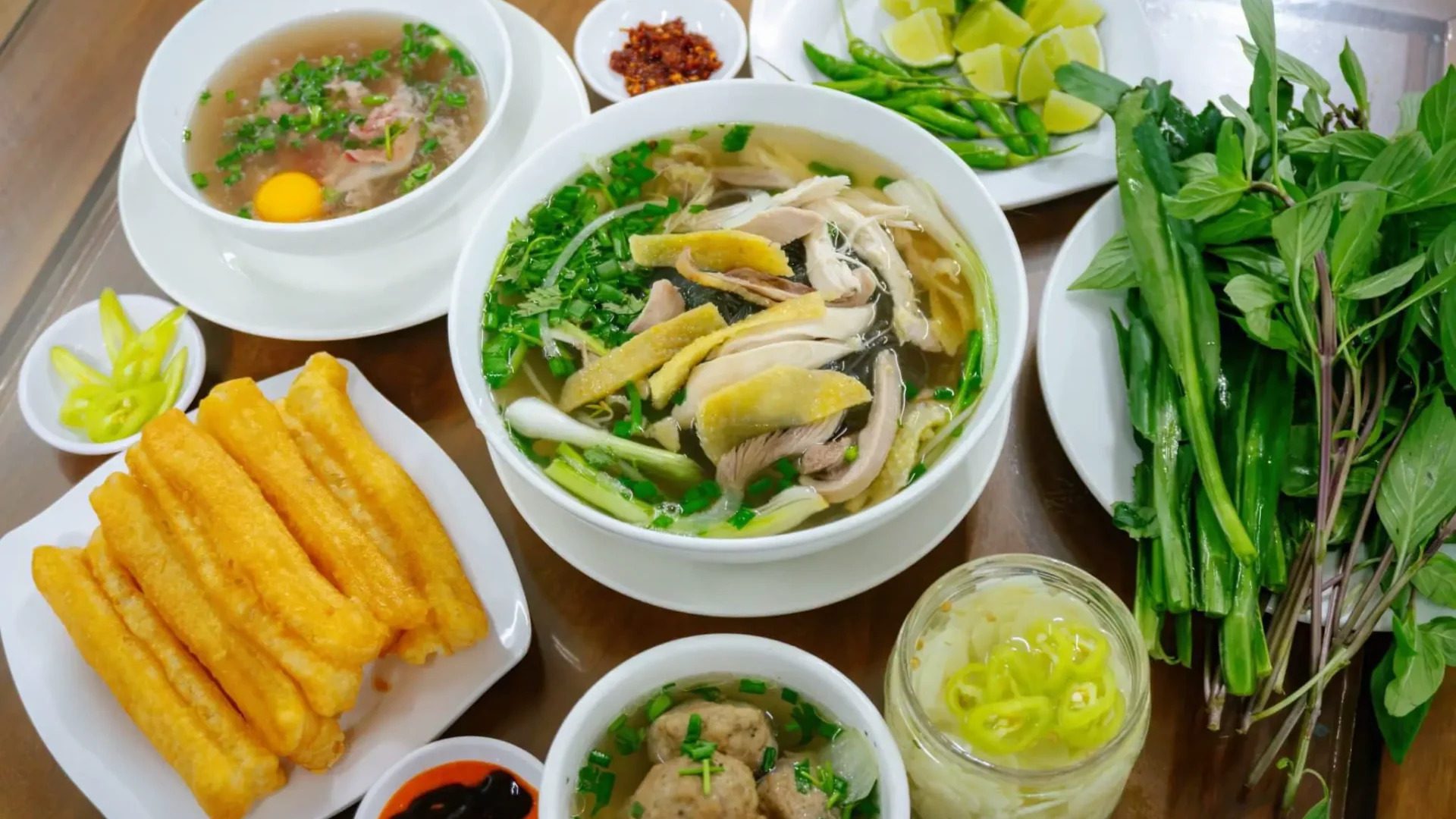 Traditional Vietnamese chicken noodle soup (Phở Gà) with fresh herbs, fried dough sticks, and chili – a must-try street food in Nha Trang.